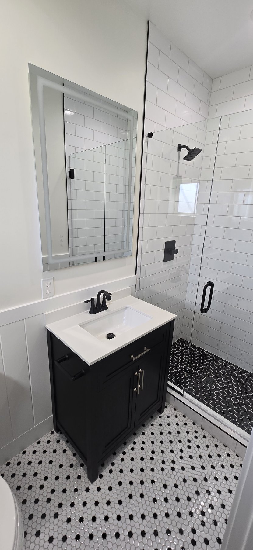 Real photo of secondary bathroom with black and white hex tile