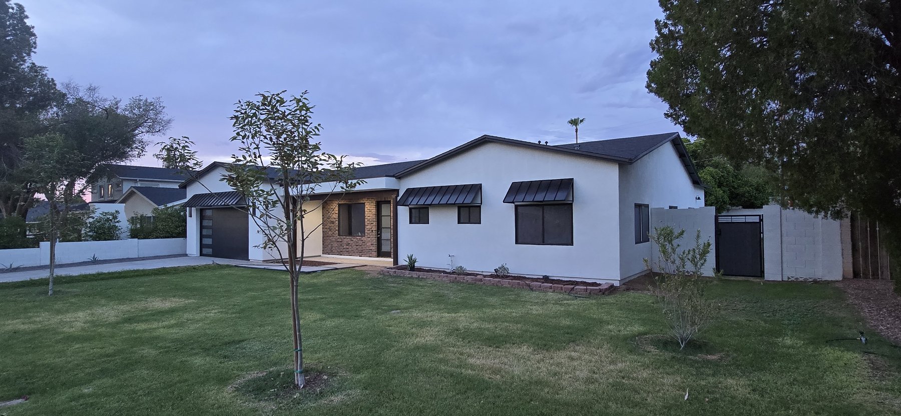 Real photo of front exterior at dusk, wide yard view
