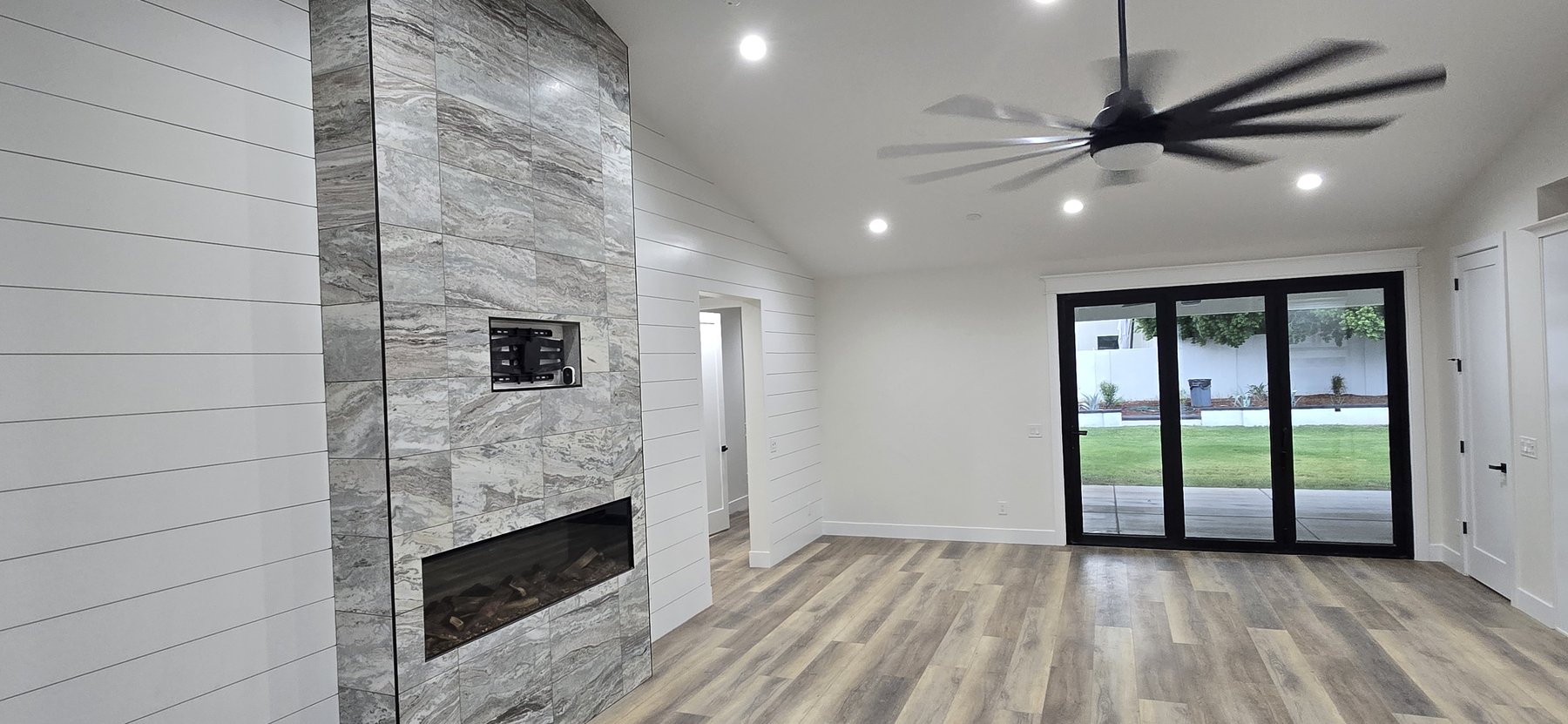 Real photo of vaulted great room with fireplace and slider to backyard